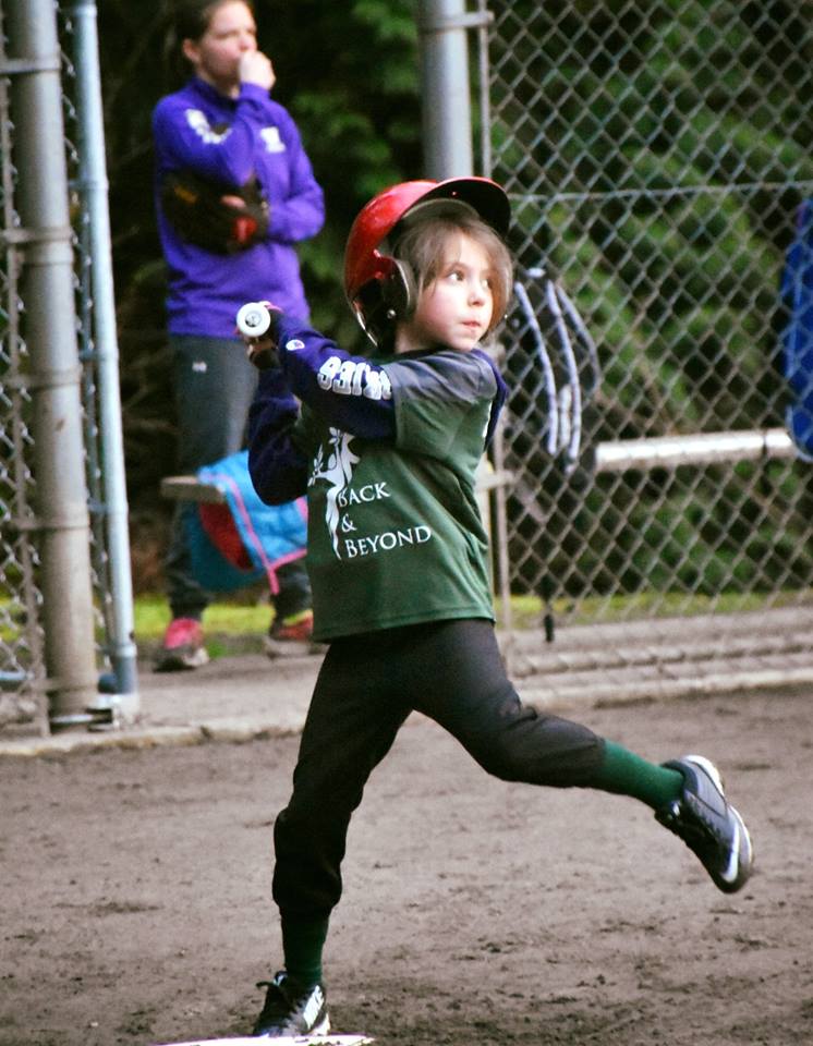 Small girl taking a big swing during softball game