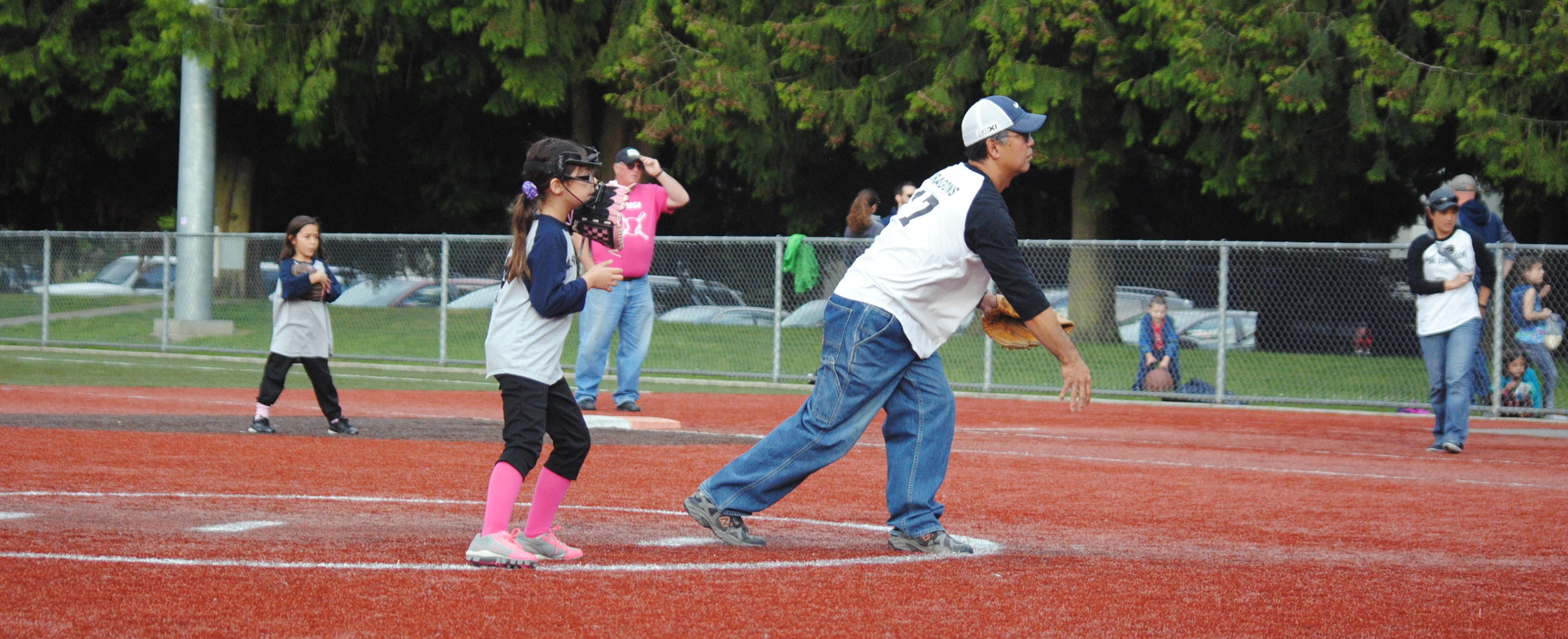 coach pitching center in photo is a coach pitching a slow pitch softball game