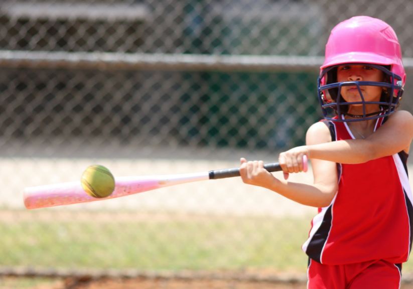 girls swinging at a softball with pink helmet on with a red blank jersy on